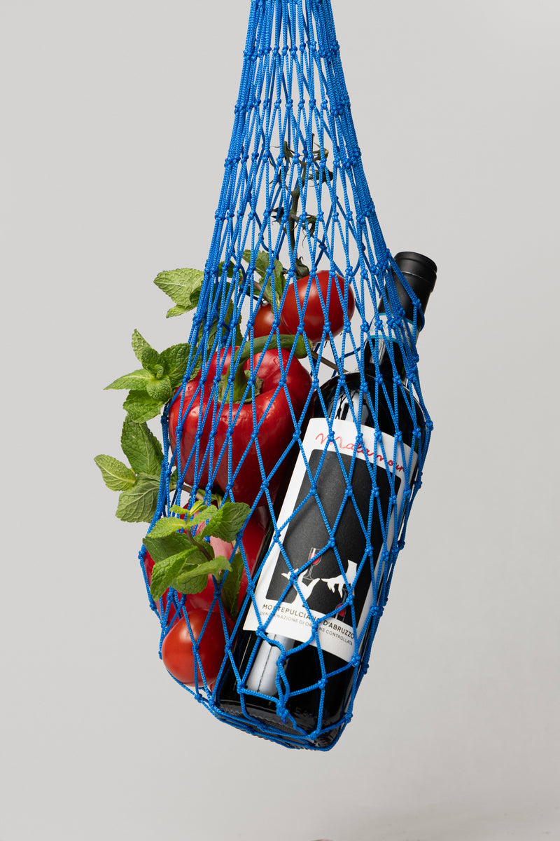 Italian wine bottle in market bag with fresh tomatoes — authentic Italian Abruzzo lifestyle
